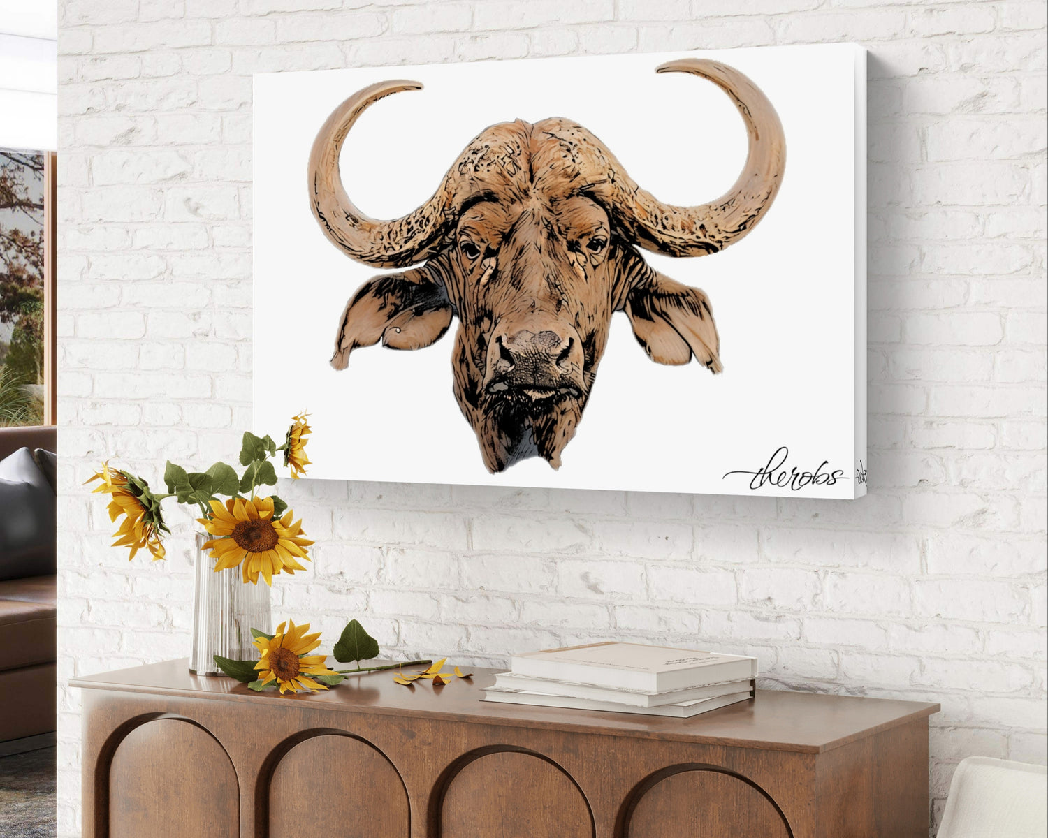 Canvas print of a buffalo head on a white brick wall above a wooden console table with decorative items.