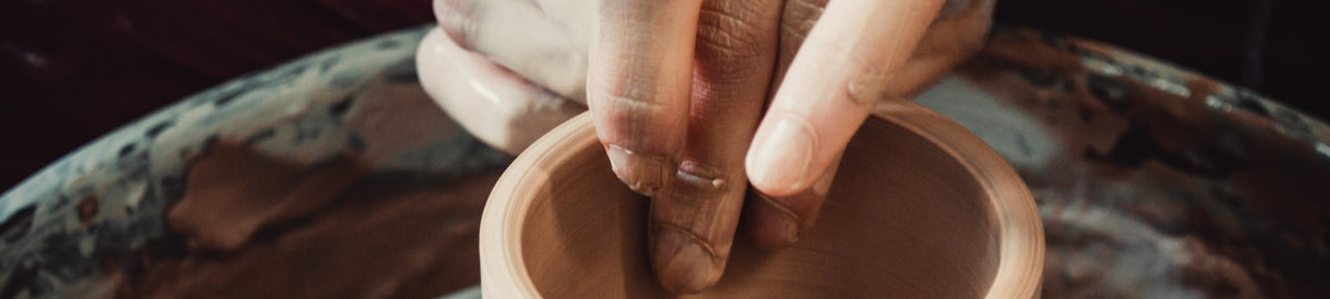 HD Printing UK Colour Ceramic Mugs. Person shaping a clay pot on a pottery wheel
