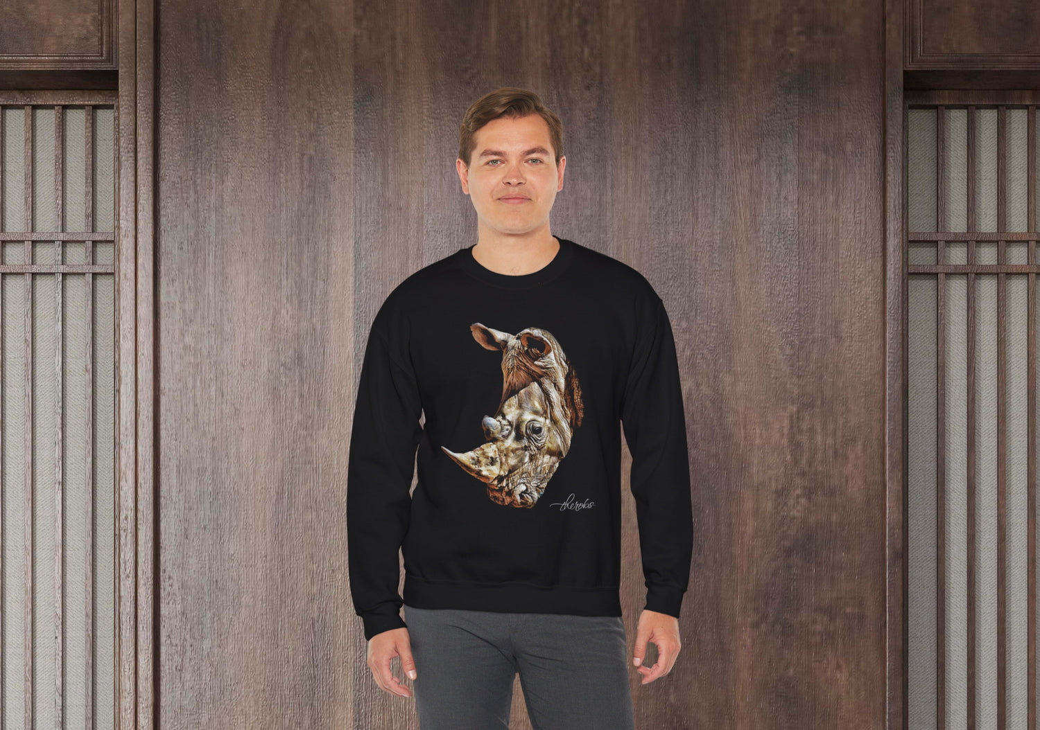 Man wearing a black sweatshirt with a graphic design in front of a wooden paneled wall.